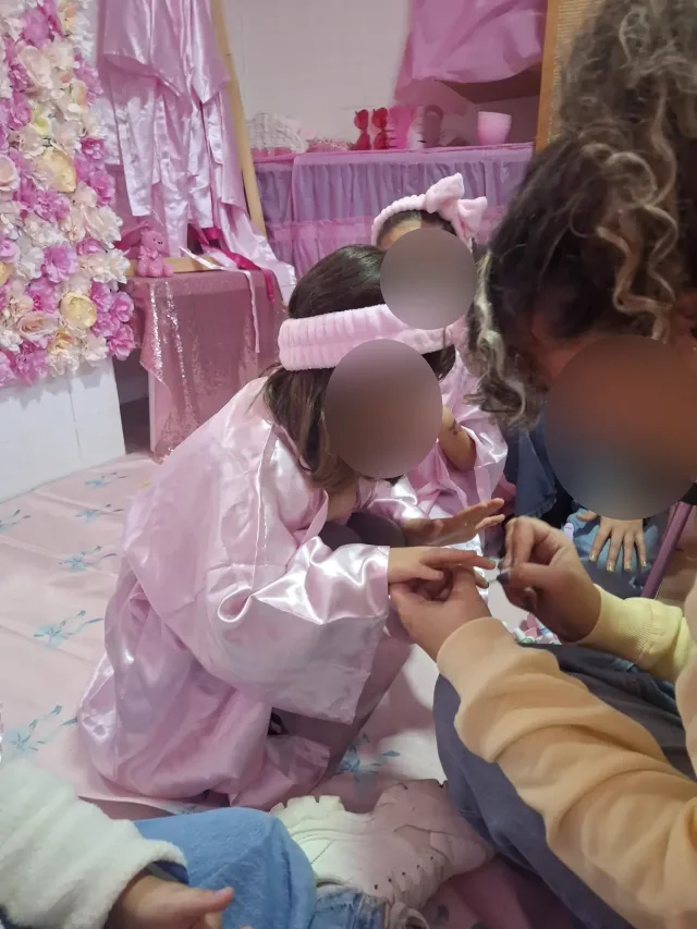 Meninas de roupão a pintar as unhas numa festa spa. As caras estão desfocadas.