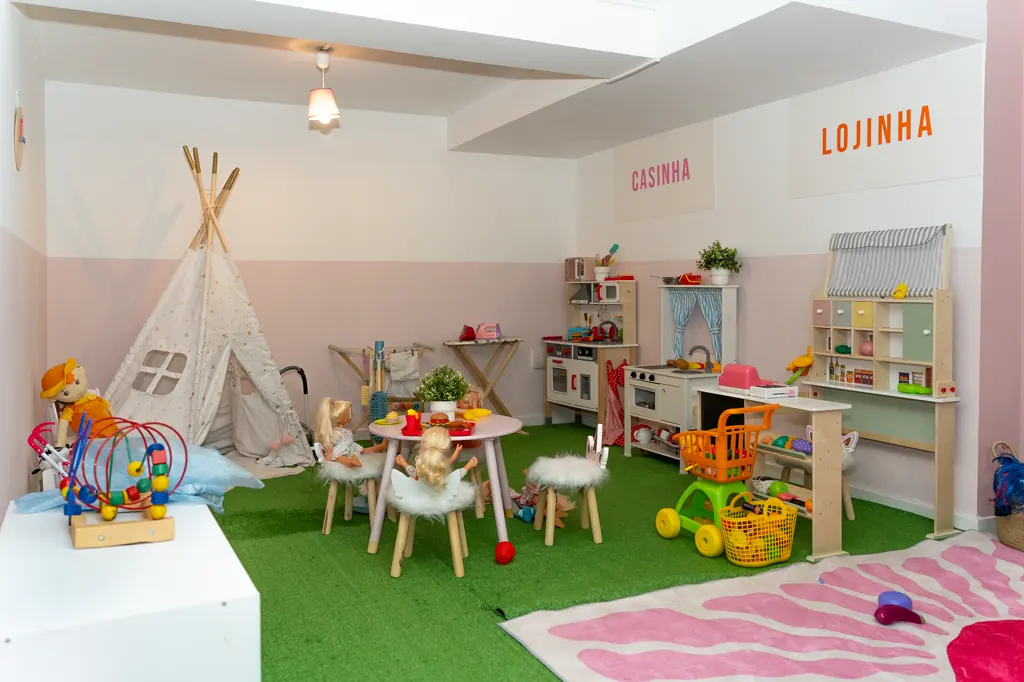 Sala de brincar da Boomerang Land: tenda tipi, Casinha e Lojinha de brincar, mesinhas com bancos e relva sintética.