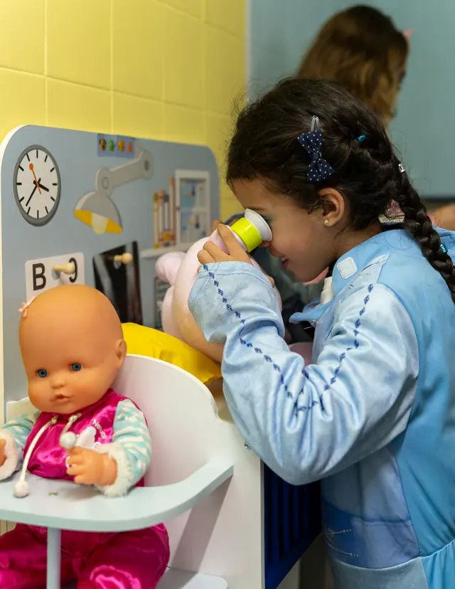 Menina com bata a examinar um boneco no Veterinário.